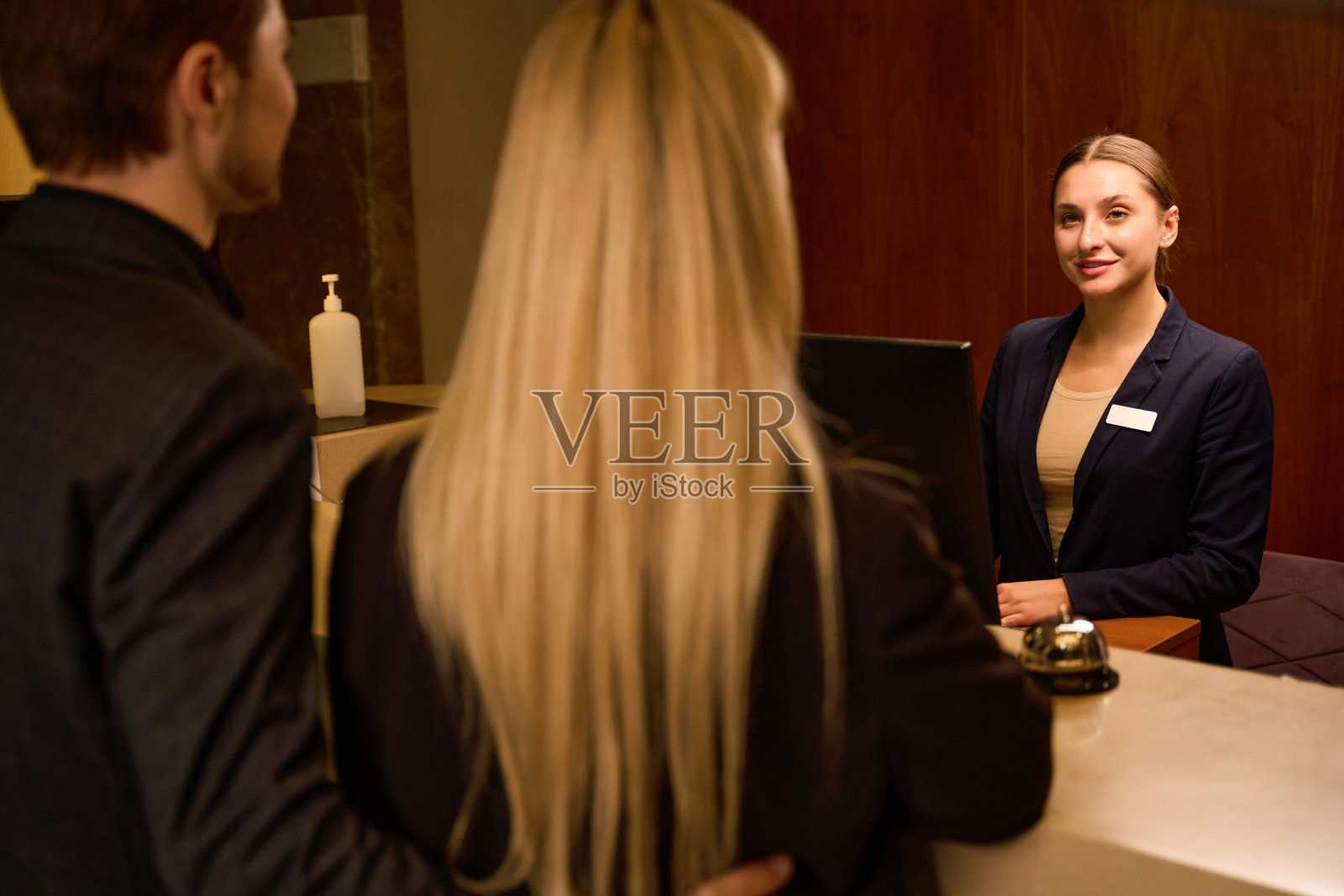 微笑的接待员在接待处迎接年轻的夫妇照片摄影图片