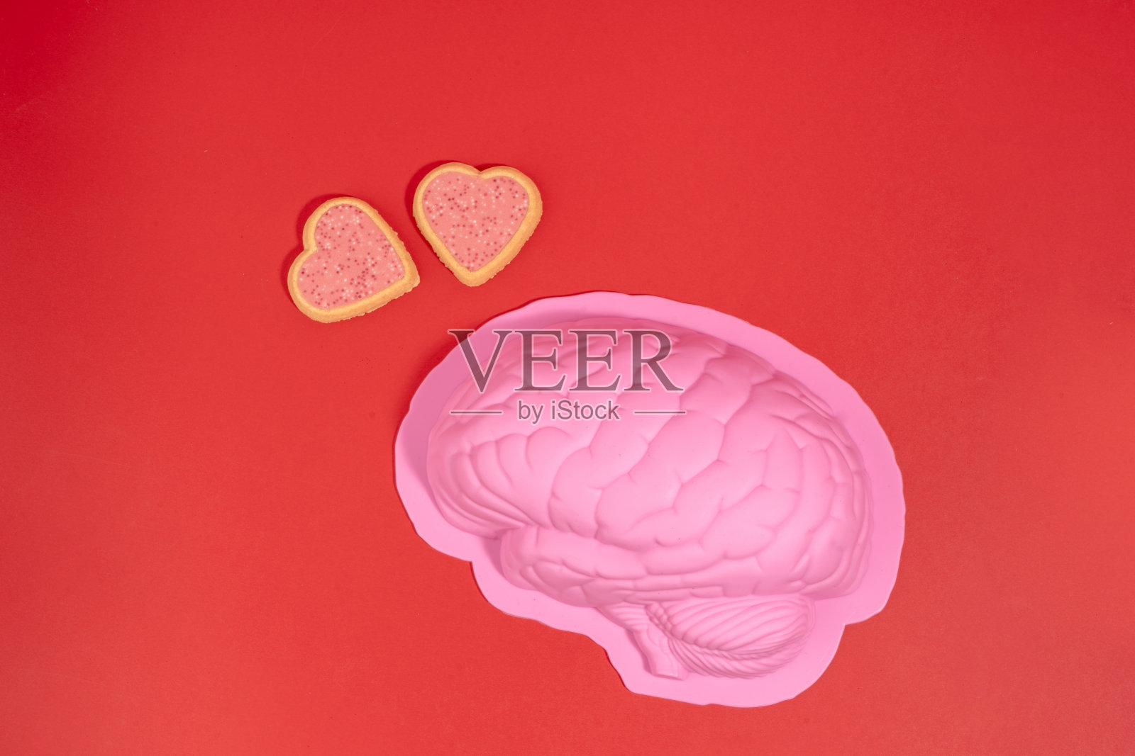 在爱情概念中，情人节的床上有粉红色的大脑和红色背景上的粉红色饼干心照片摄影图片