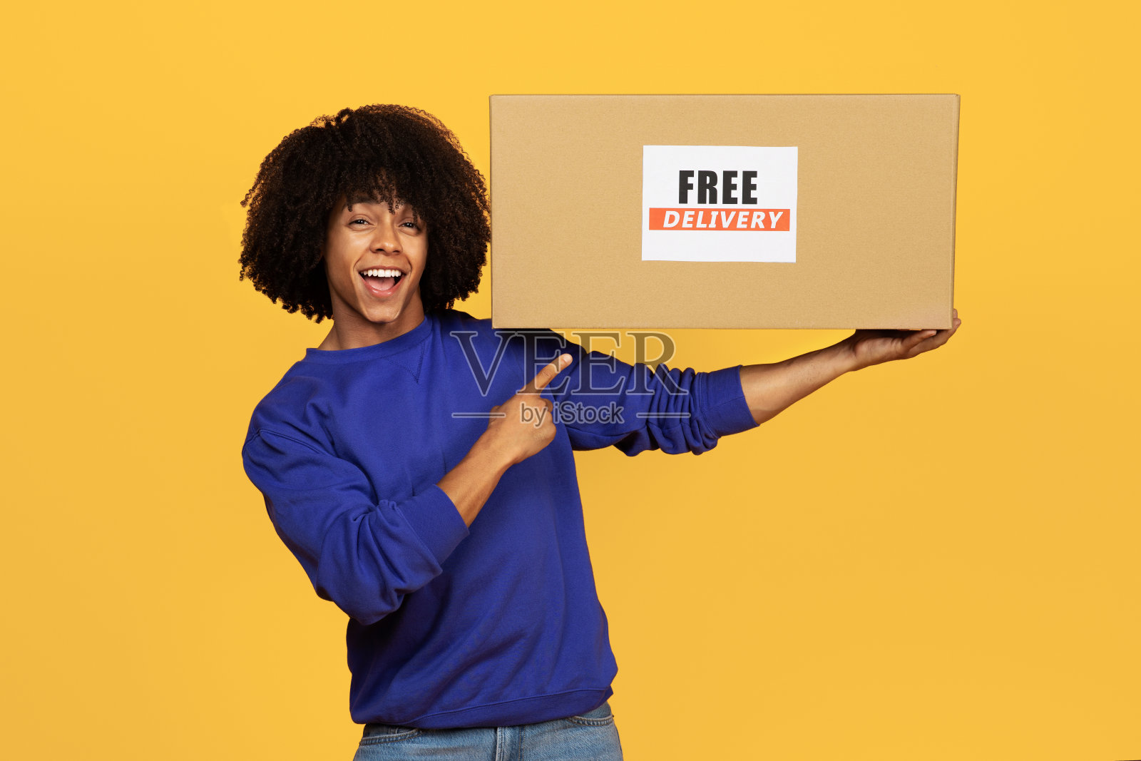 快乐的黑人指着纸板箱，上面写着免费送货的文字照片摄影图片