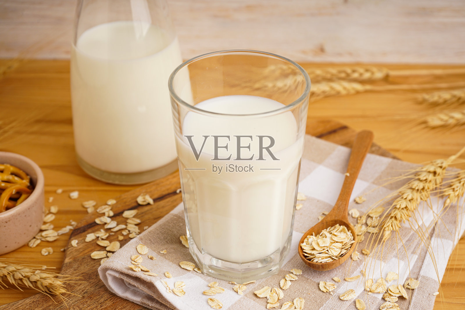 木桌上的玻璃杯和一壶鲜牛奶，衬托着彩色的背景。照片摄影图片