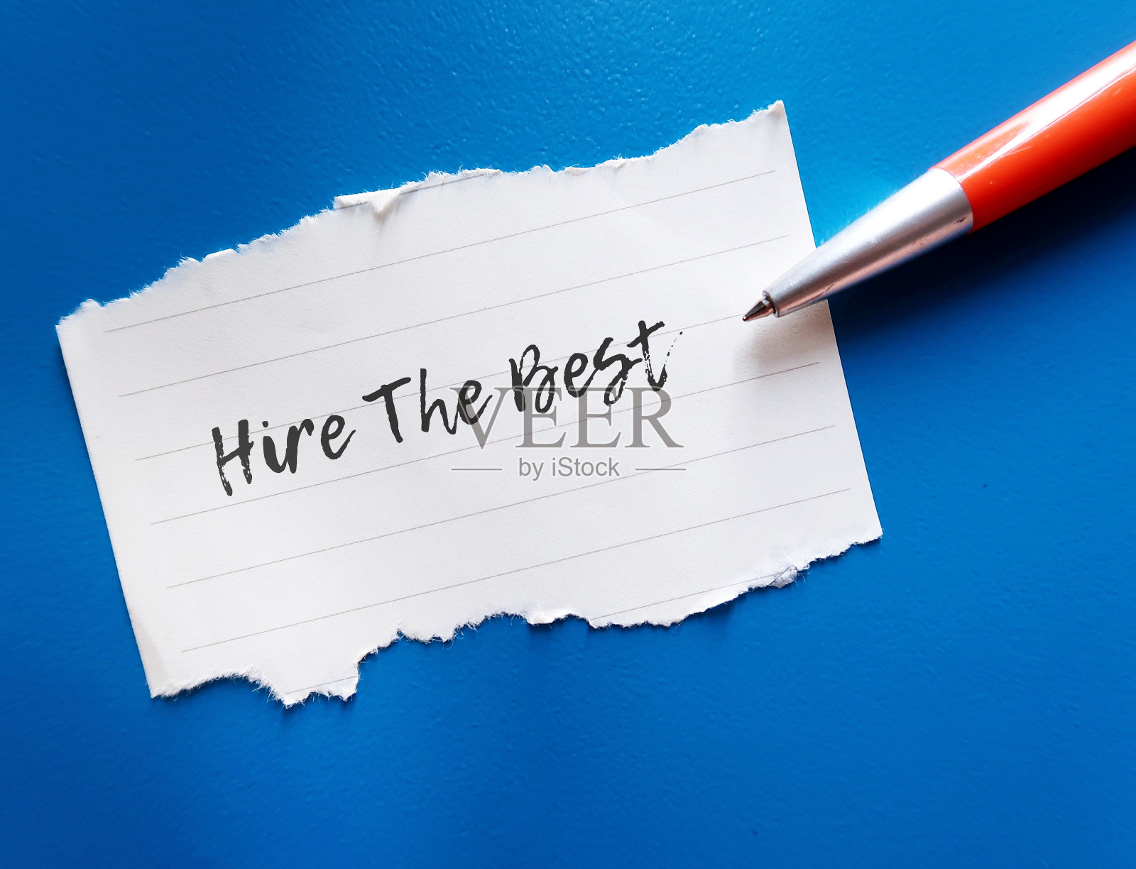 蓝底橙笔在纸上写“雇佣最好的人”，意思是企业老板需要雇佣他们所在领域的顶尖人才，以取得未来的成功照片摄影图片