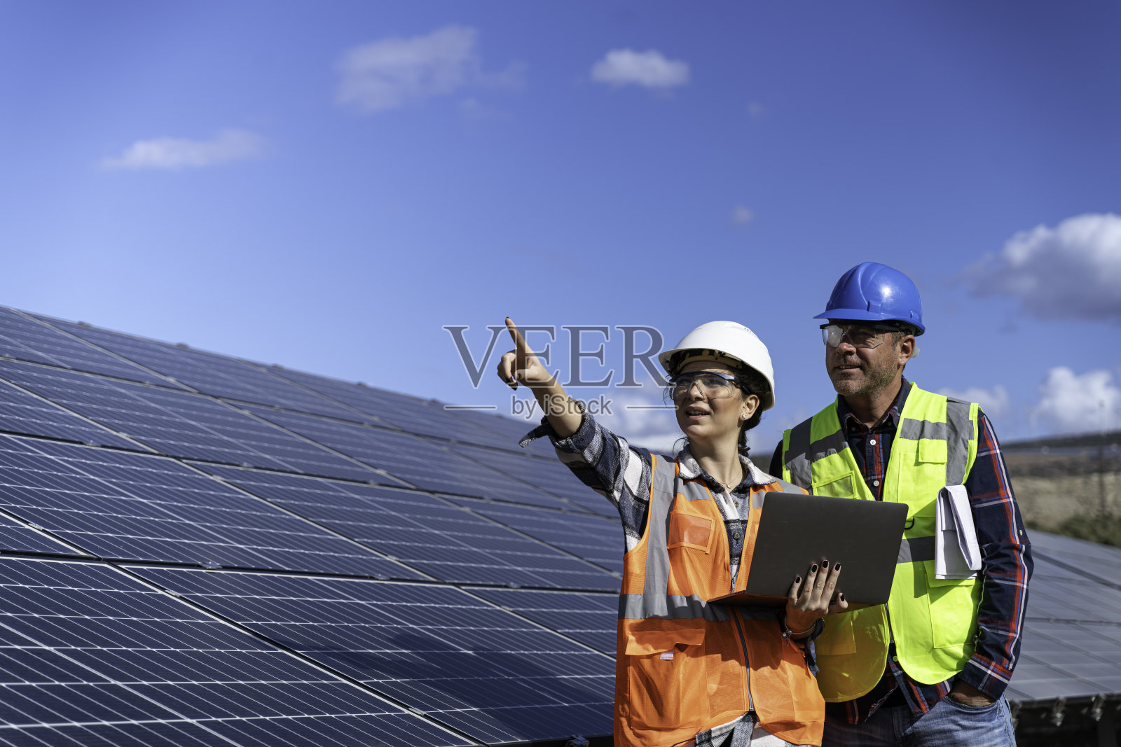 年轻的工程师检查太阳能板的安装，在现场用图纸检查，并在电脑上记录检查数据。照片摄影图片