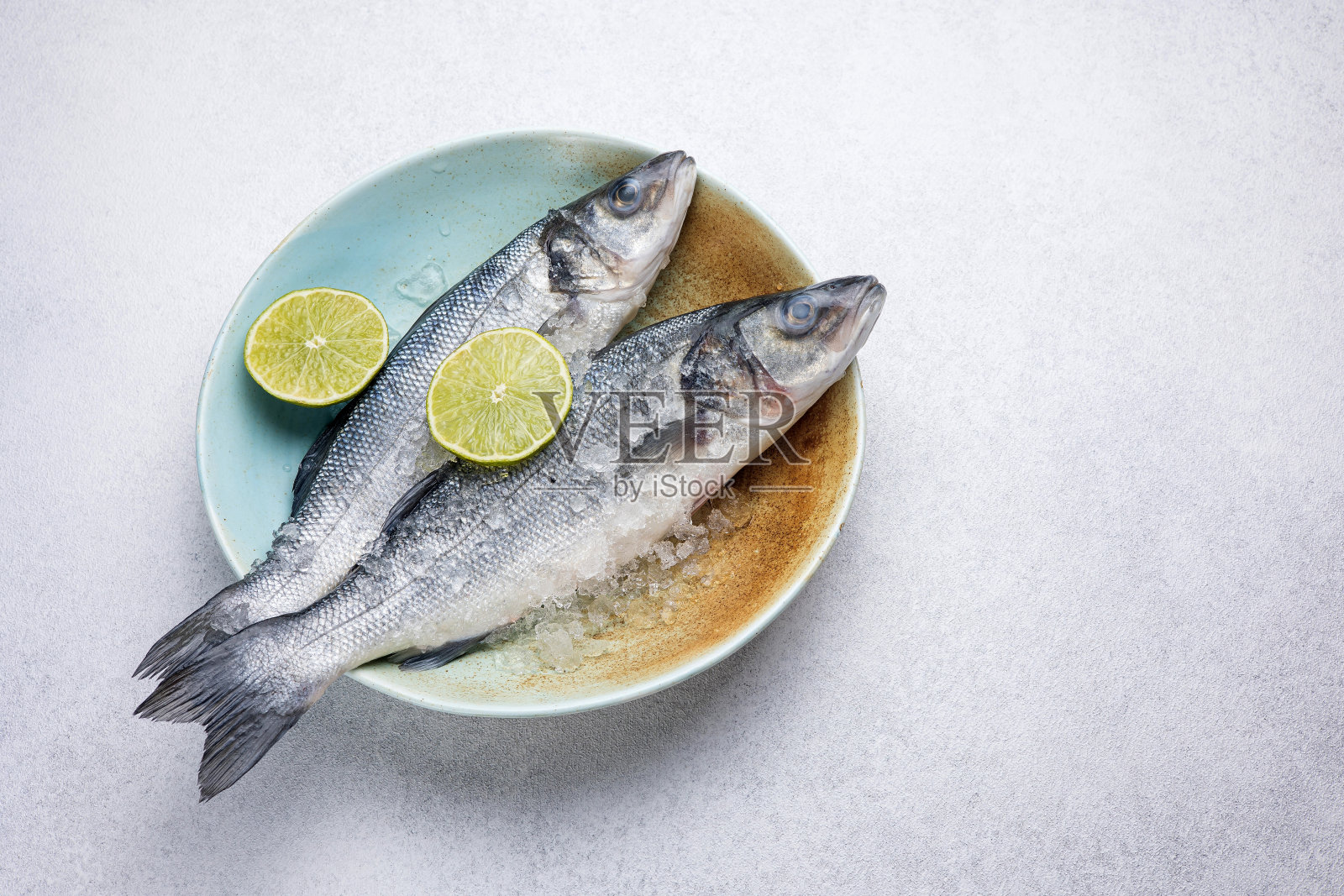 盘中新鲜的生鲈鱼。近距离照片摄影图片