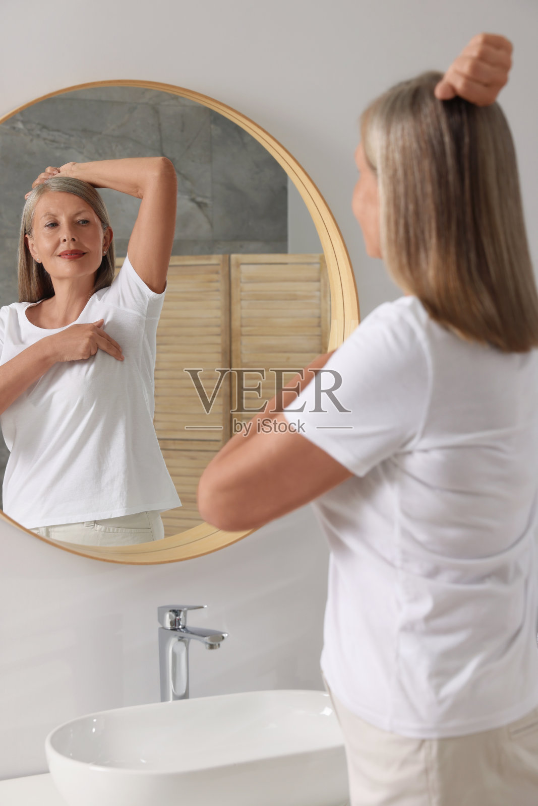 漂亮的老女人在浴室镜子前做乳房自检照片摄影图片