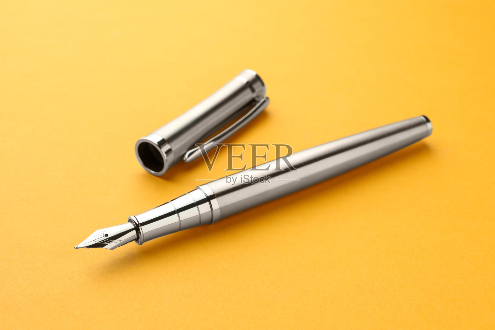 时尚的银色钢笔与黄色背景帽照片摄影图片