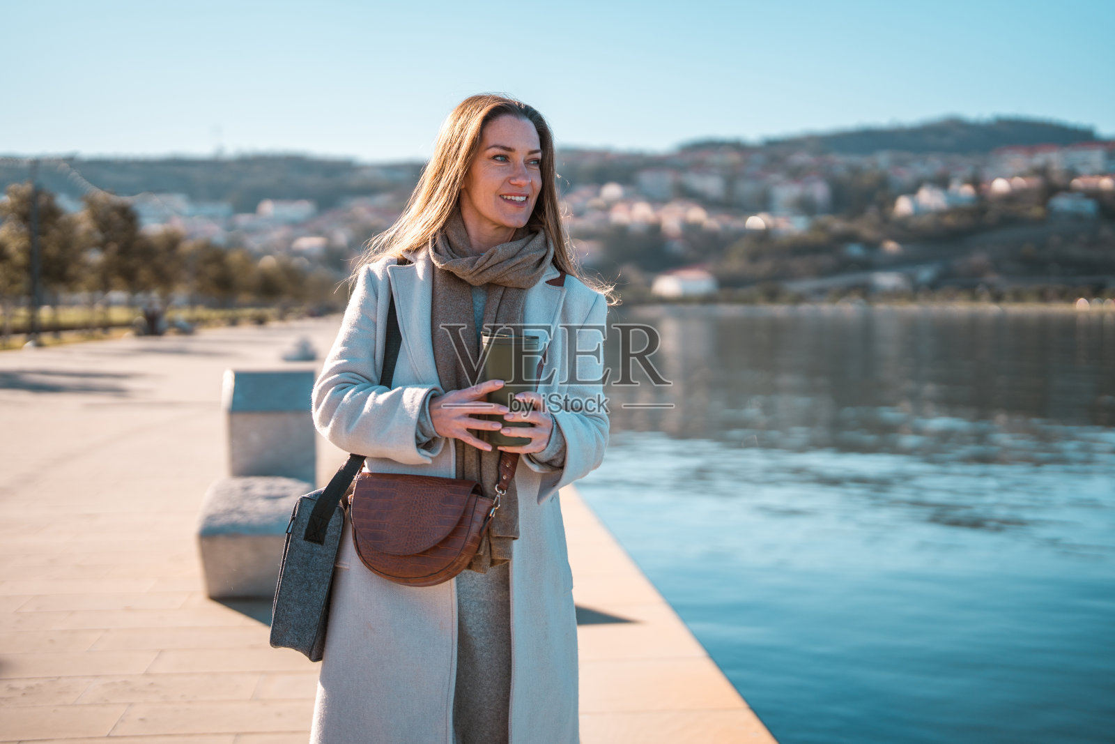 水边拿着智能手机的中年白人女性照片摄影图片