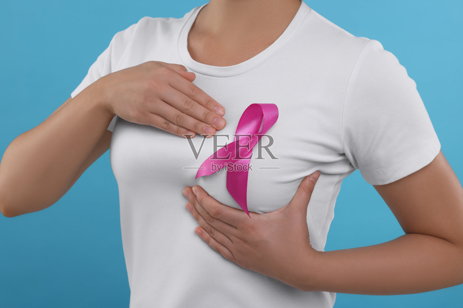 浅蓝色背景上系粉色丝带的女人，特写。乳腺癌意识照片摄影图片