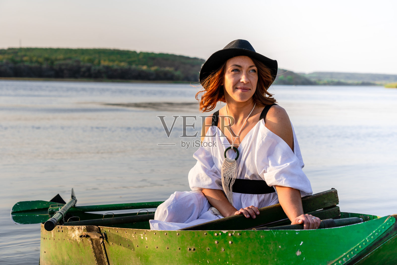 快乐的新娘戴着黑帽子在河上的船上照片摄影图片