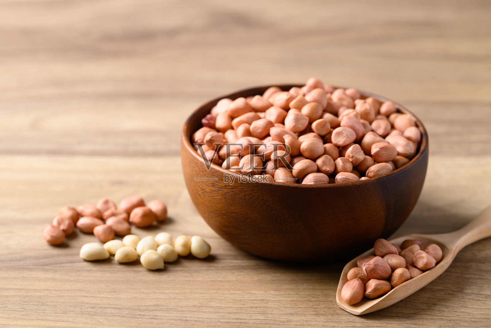 花生在碗里，勺子在木背景上照片摄影图片
