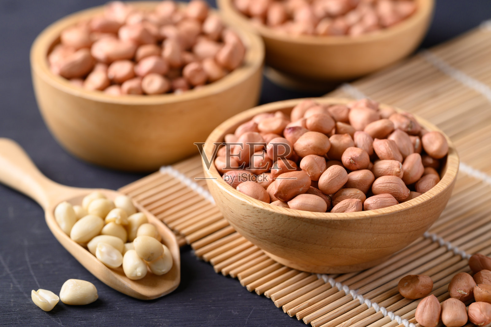 花生在木碗与勺子在黑色背景照片摄影图片