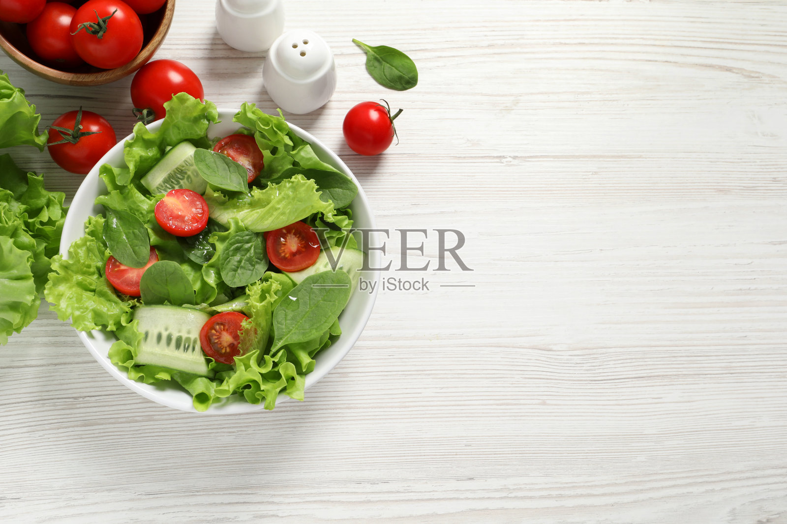 美味的蔬菜沙拉，圣女果，生菜，胡椒和搅拌器放在白色的木桌上，平铺着。文本空间照片摄影图片