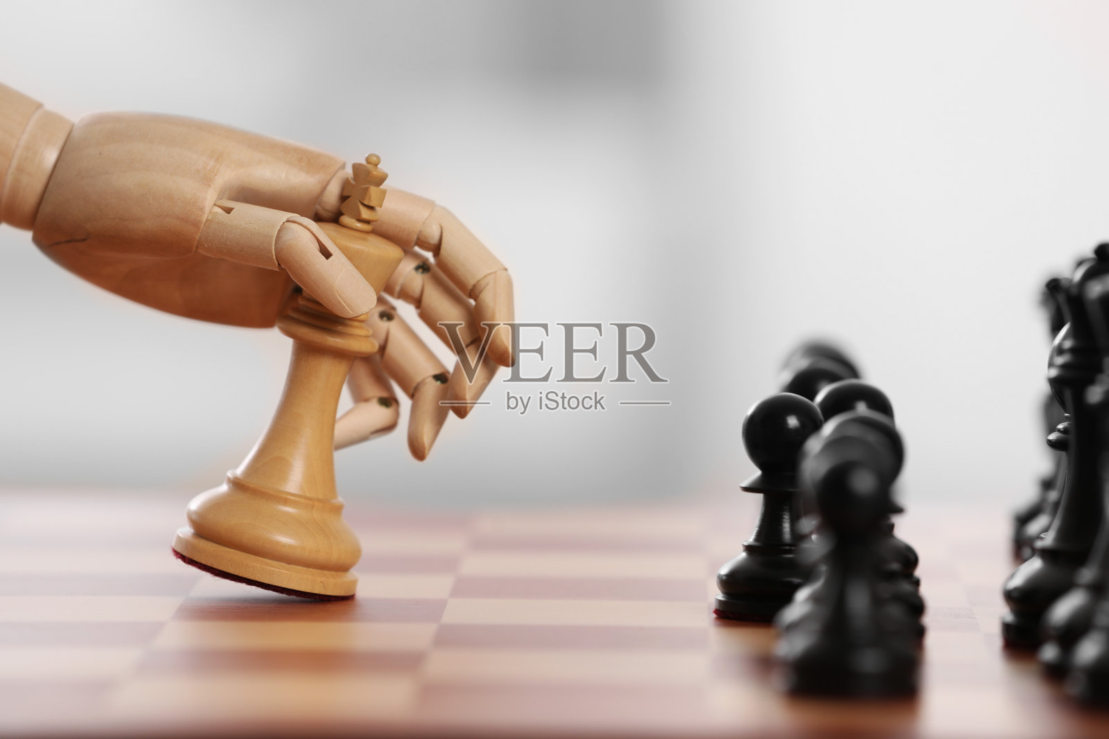 机器人移动棋盘上的棋子在浅色背景下，特写。代表人工智能的木手照片摄影图片