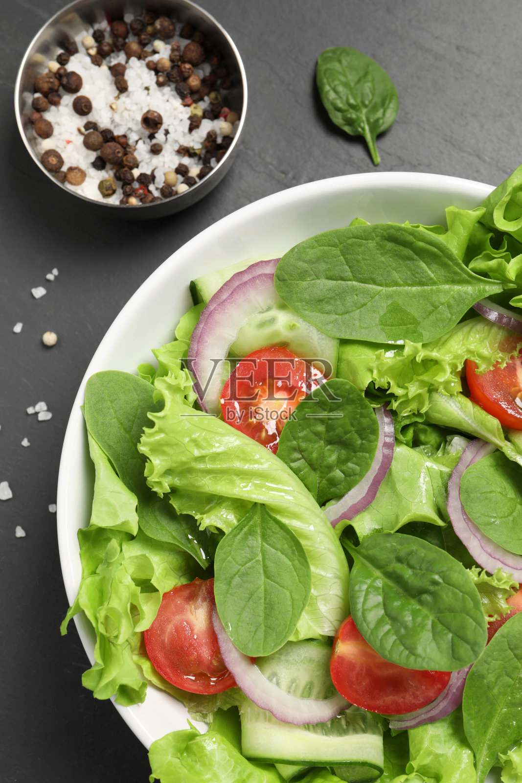 美味的蔬菜沙拉，盐和胡椒在灰色的桌子上，平铺照片摄影图片