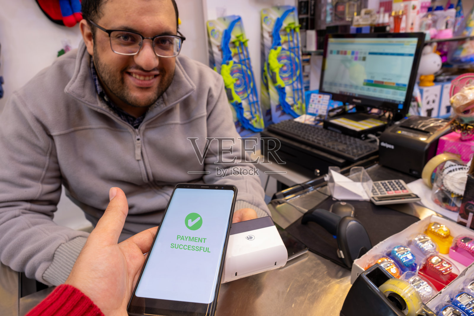 男人在书店或礼品店使用智能手机进行非接触式支付，无需物理接触即可无缝使用NFC或WiFi技术照片摄影图片