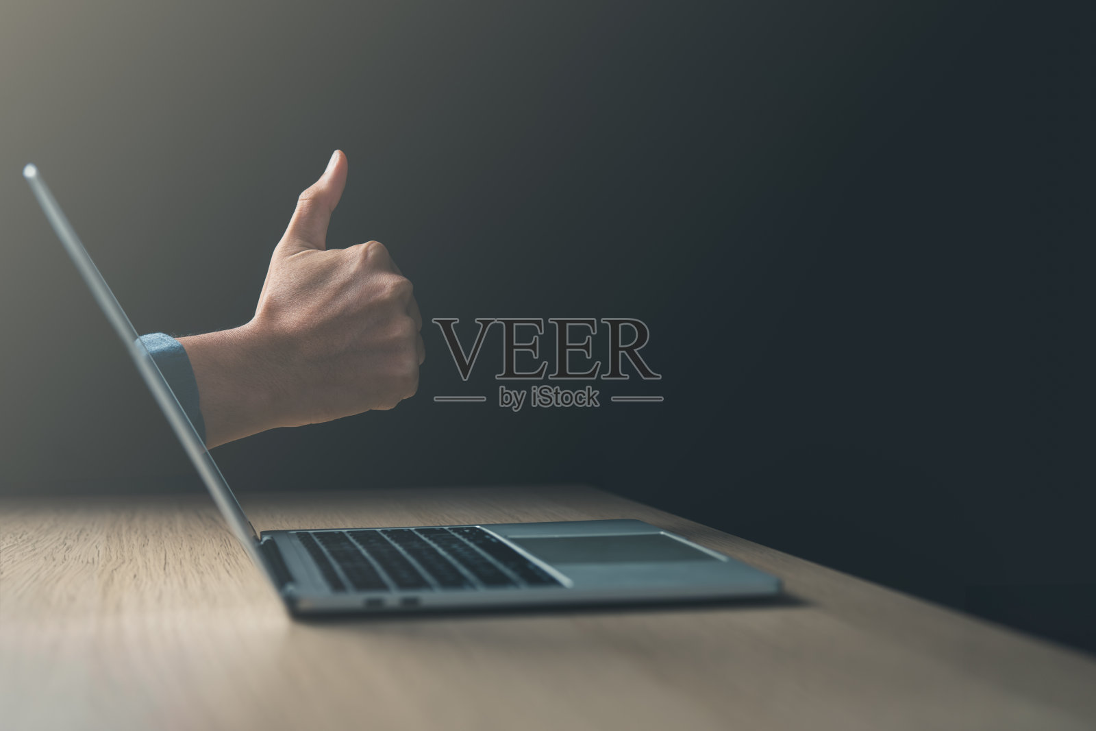 业务目标的实现和良好的工作理念。笔记本电脑上有商人的大拇指。照片摄影图片