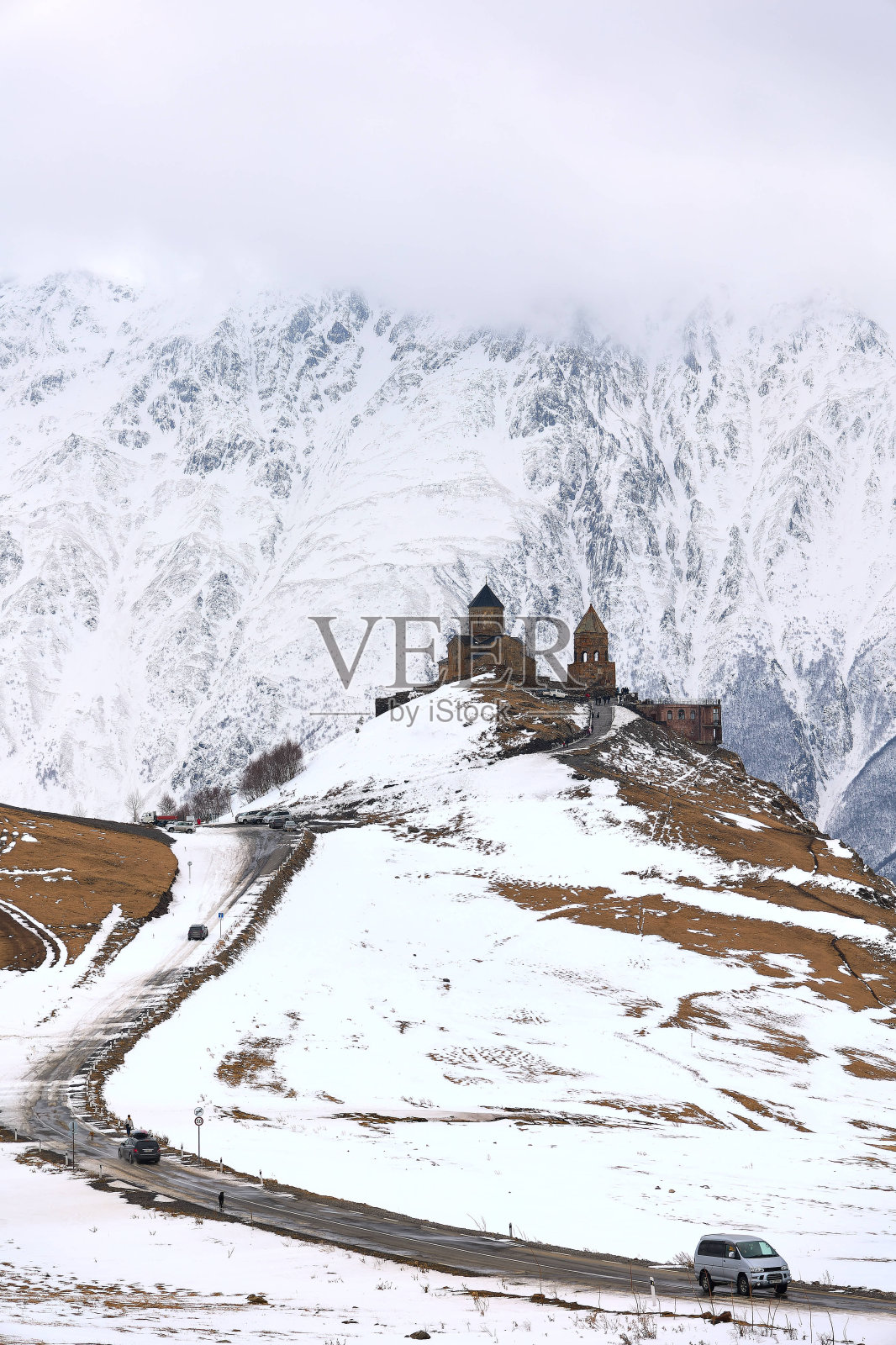 积雪覆盖的山脉背景是乔治亚州斯泰普斯明达的格盖蒂三一教堂照片摄影图片