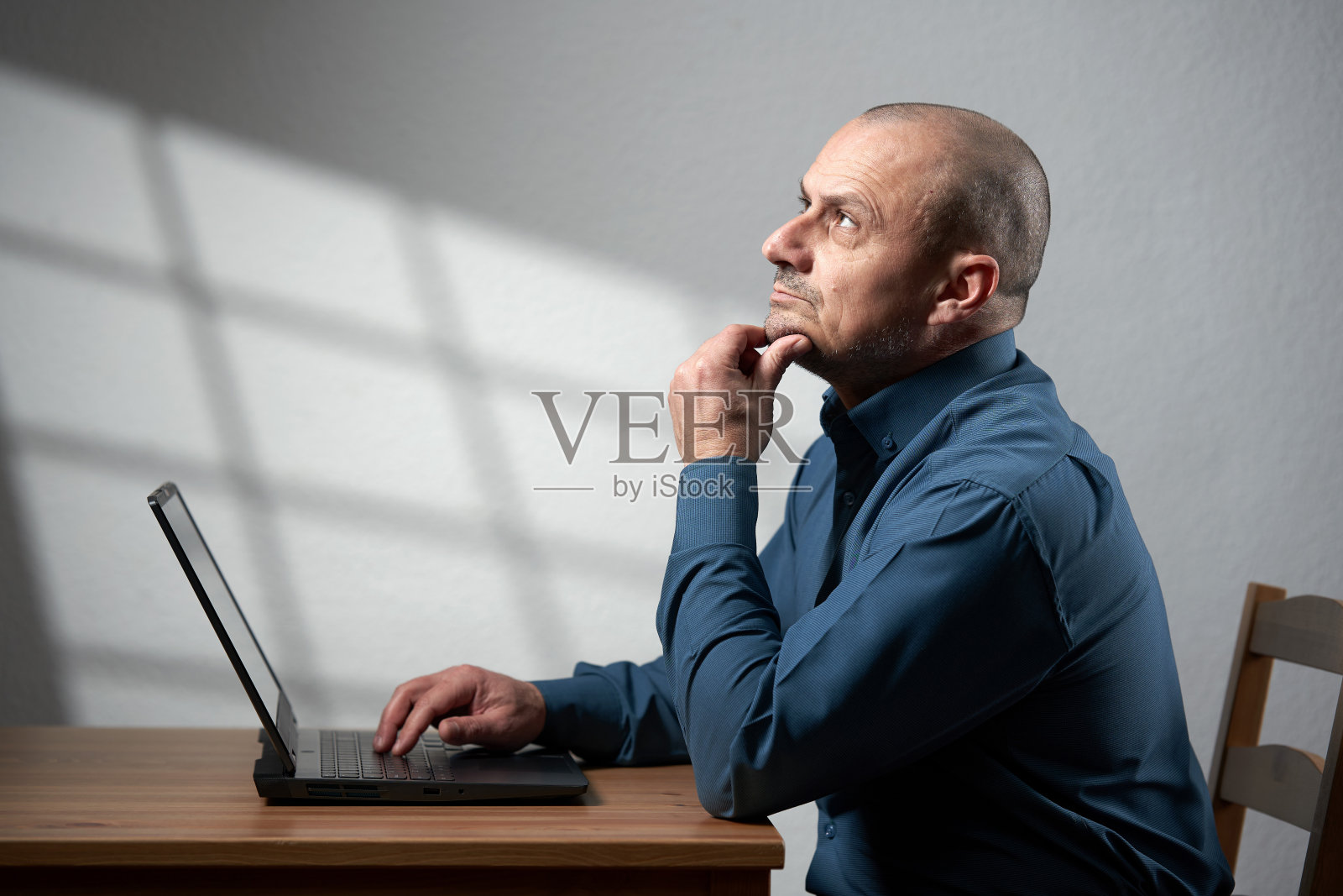 成熟的商人，桌上放着笔记本电脑，沉思着照片摄影图片