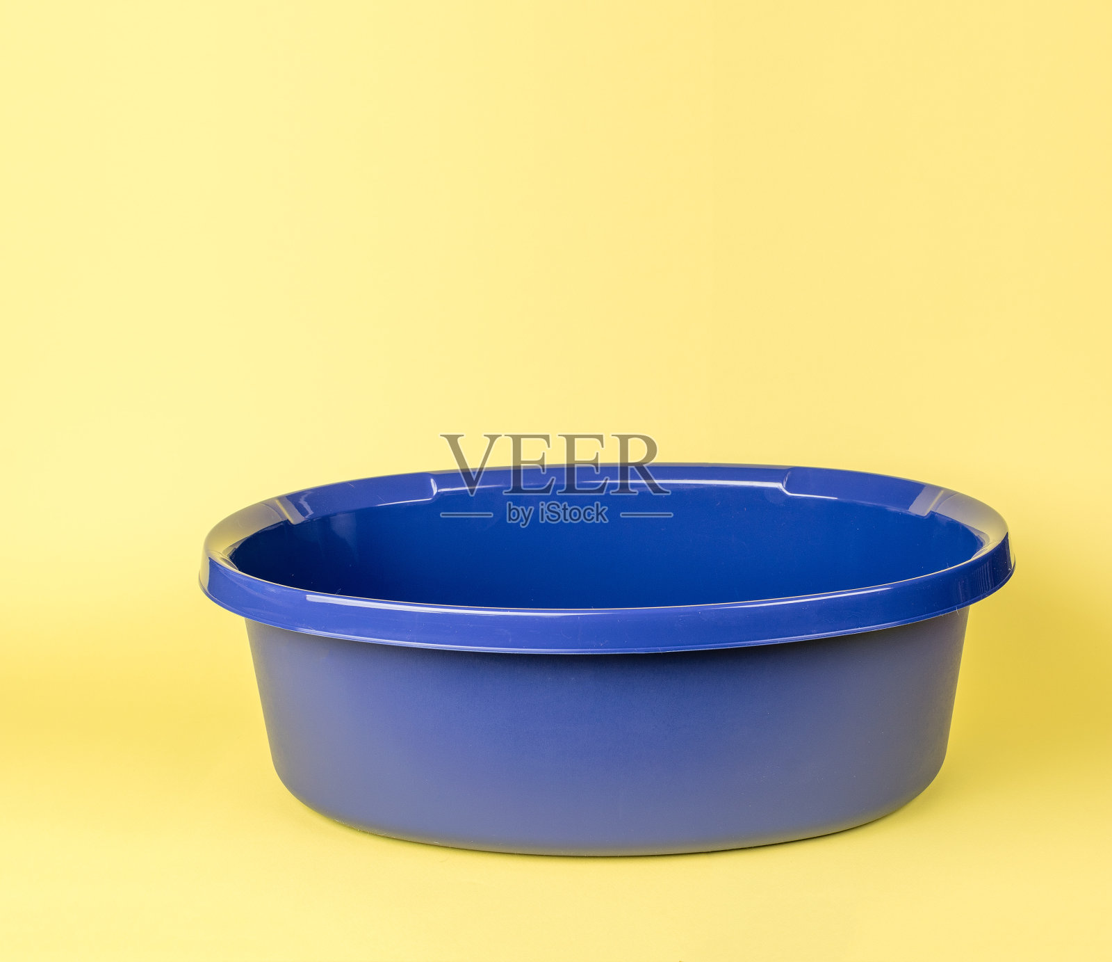 黄色背景上的蓝色空盆。照片摄影图片