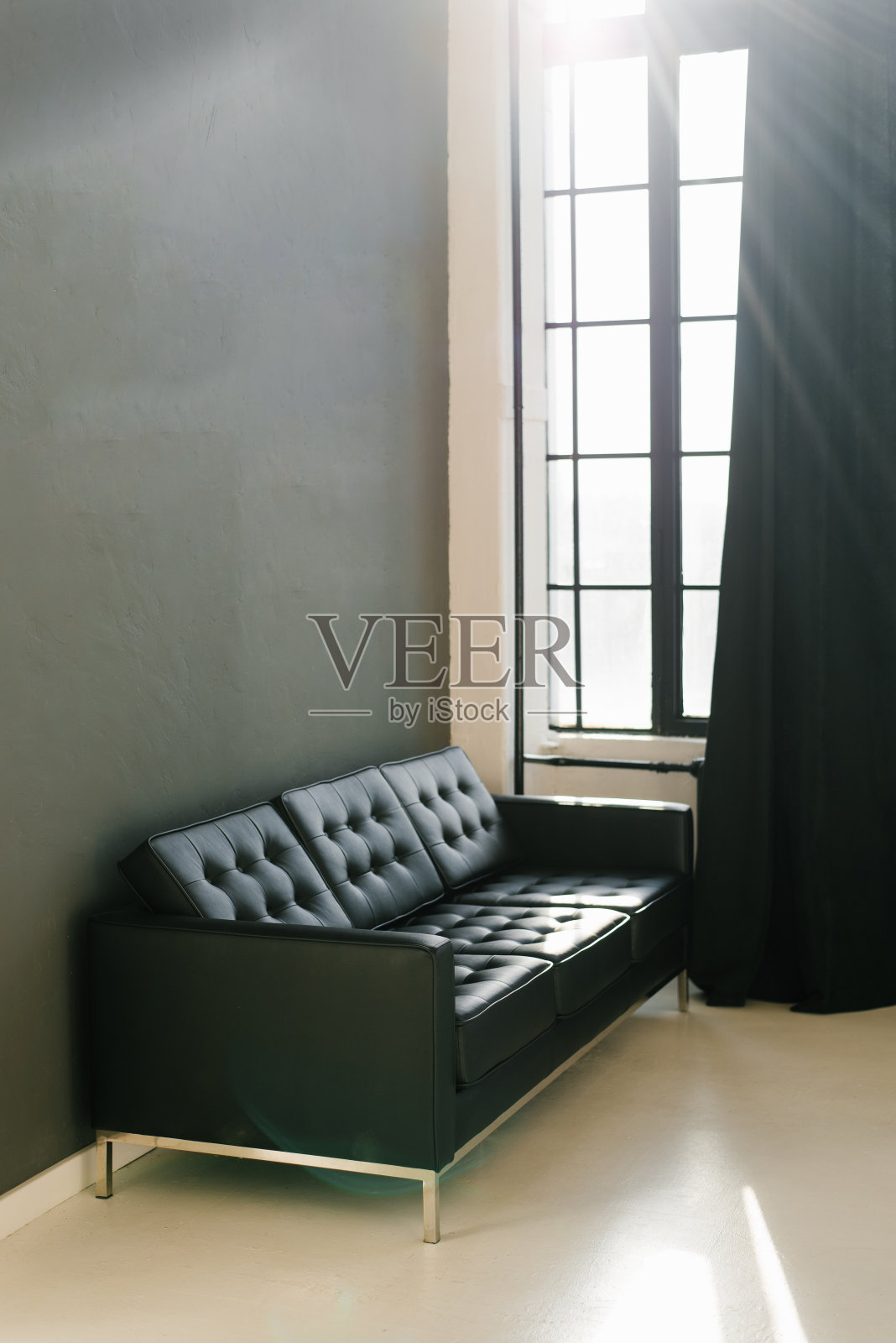 房间里摆着一张粗糙的黑色沙发，墙壁是深灰色的，窗户上挂着黑色的窗帘照片摄影图片