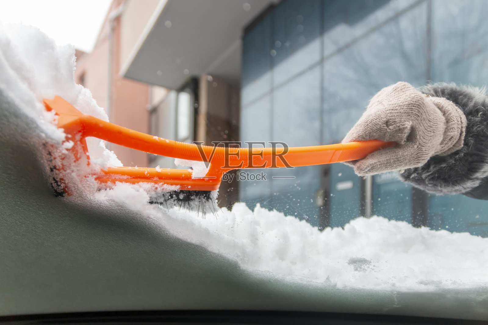冬季驾驶。一只手清理汽车挡风玻璃上的冰雪的特写。照片摄影图片