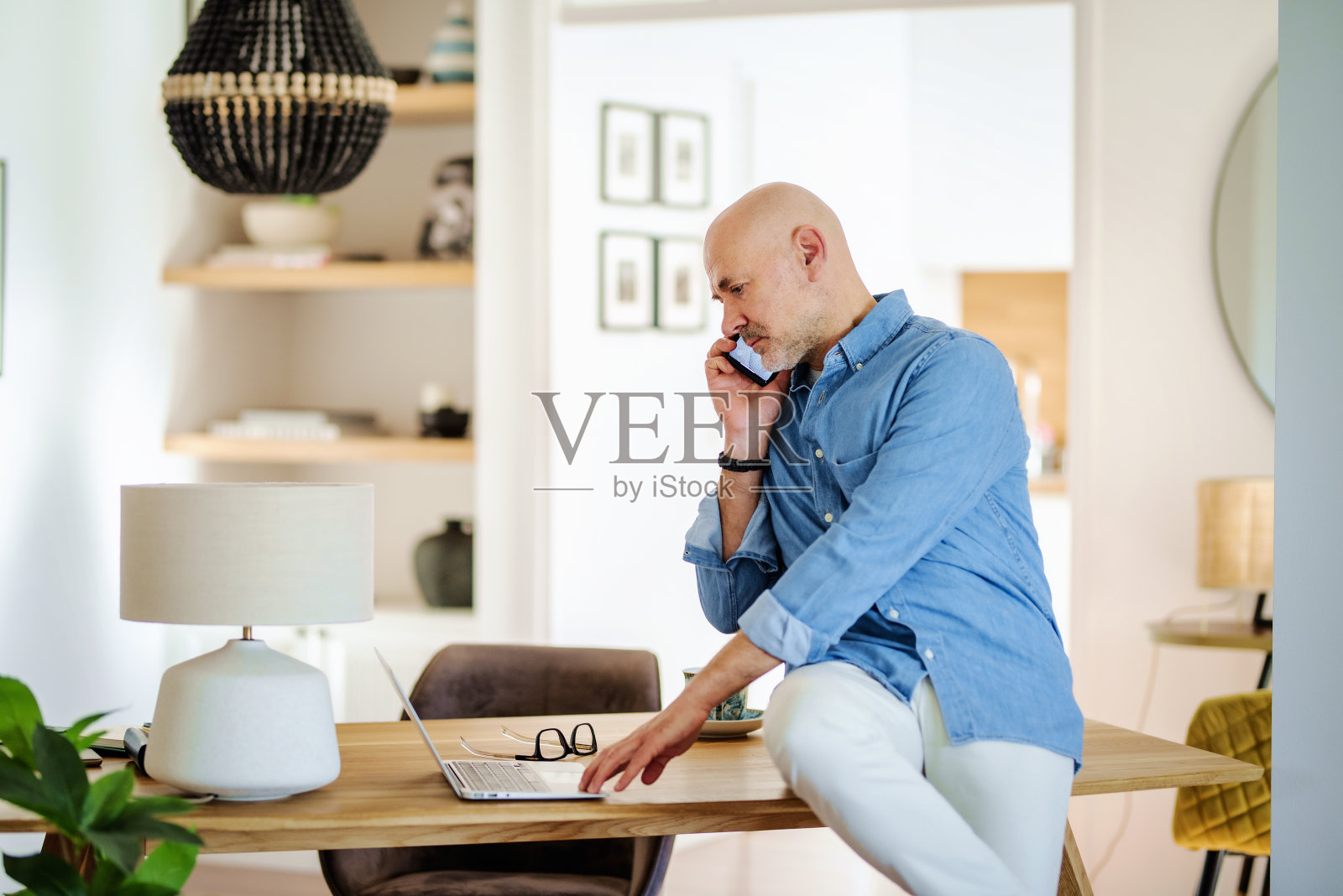 中年随意的商人，坐在办公桌前，在家打电话照片摄影图片