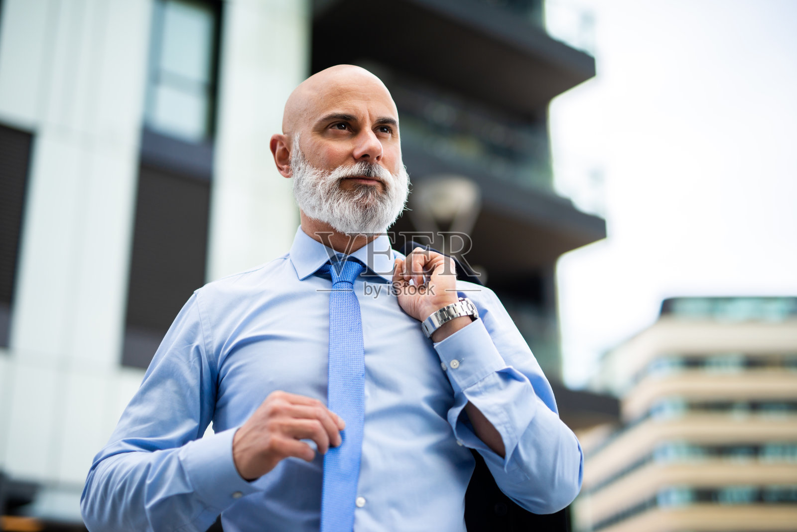 成熟的秃顶时尚的商人肖像与白胡子在户外拿着他的外套照片摄影图片