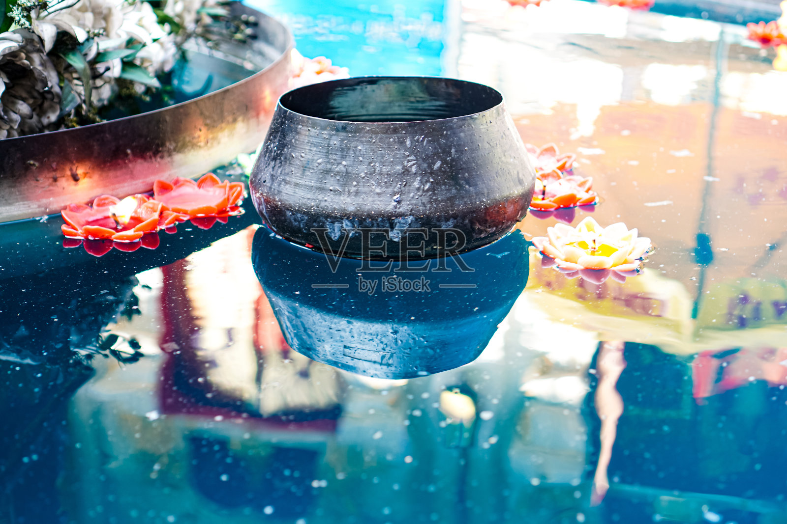 图为在泰国清迈的一座寺庙里，一个和尚的布施钵漂浮在一个盆里，用于传统的佛教功德仪式。照片摄影图片