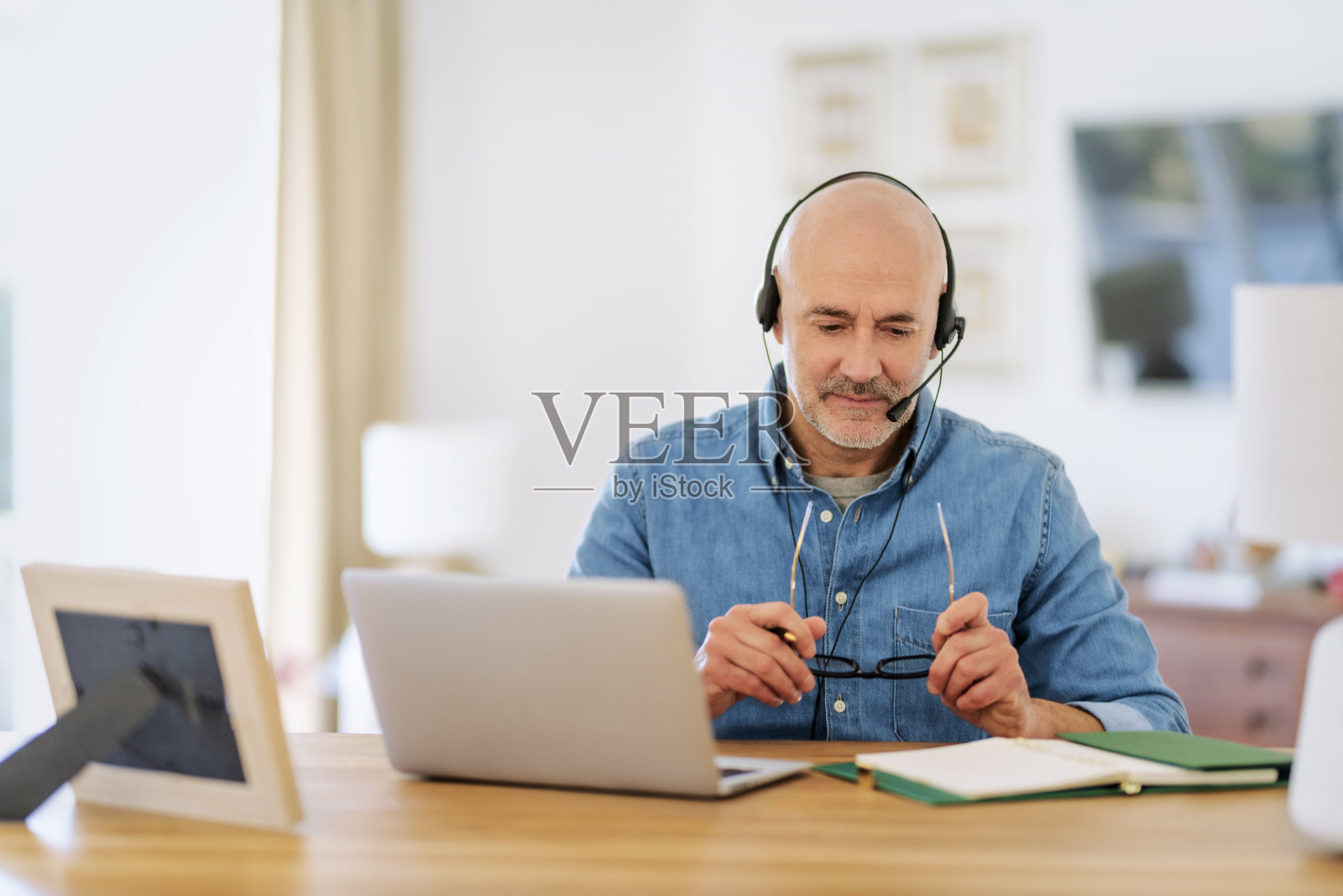 男性客户服务助理商人戴耳机，使用笔记本电脑工作照片摄影图片