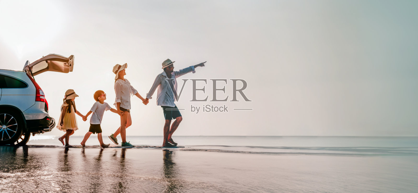 一家人在野餐。假日日落时，父母抱着儿子和女儿在海滩上。照片摄影图片