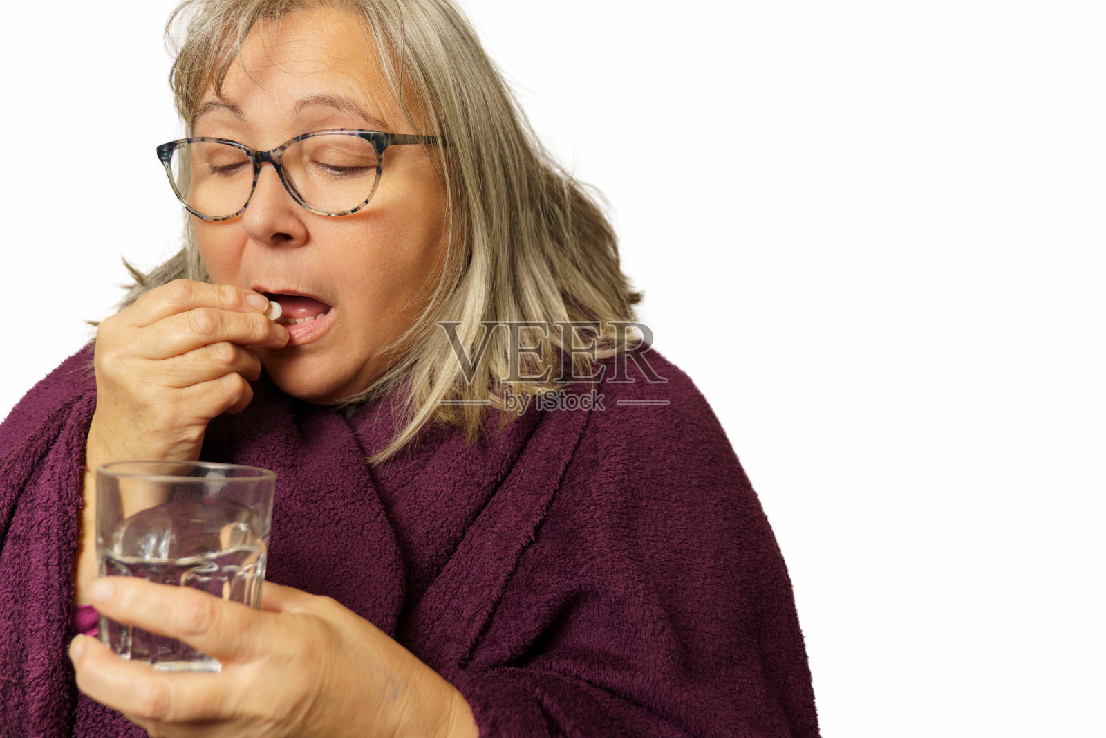 一个裹着毯子服药的成熟女人照片摄影图片