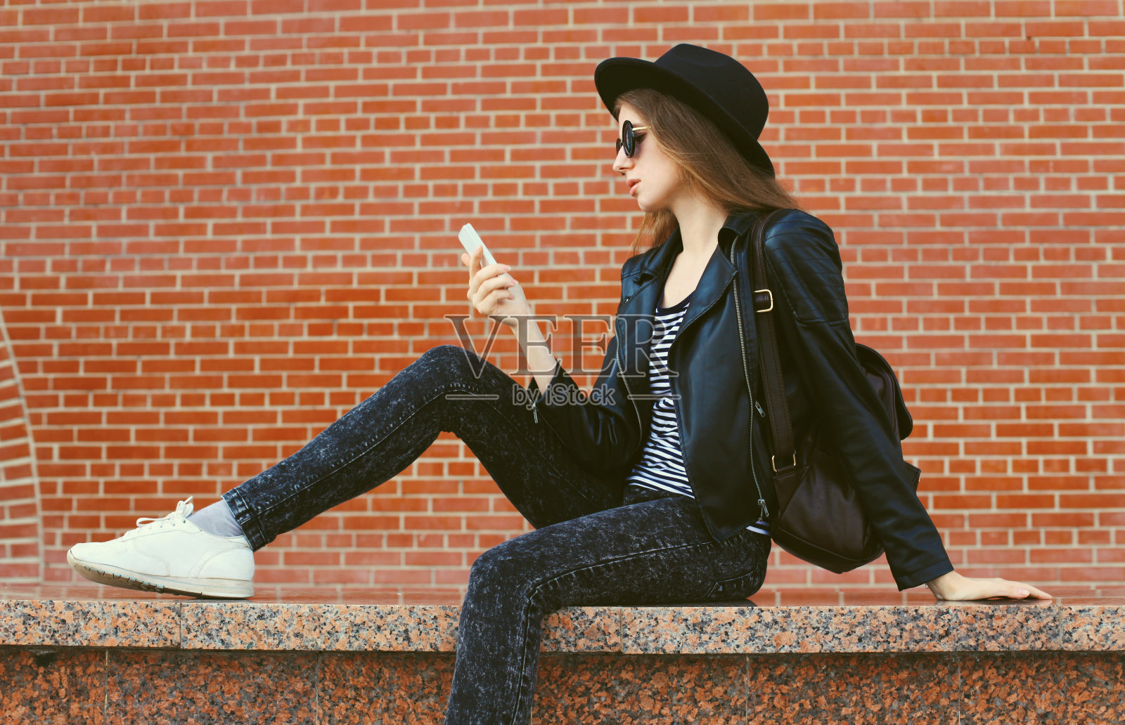 20多岁的现代白人年轻女性模特在城市街道上拿着手机看设备照片摄影图片