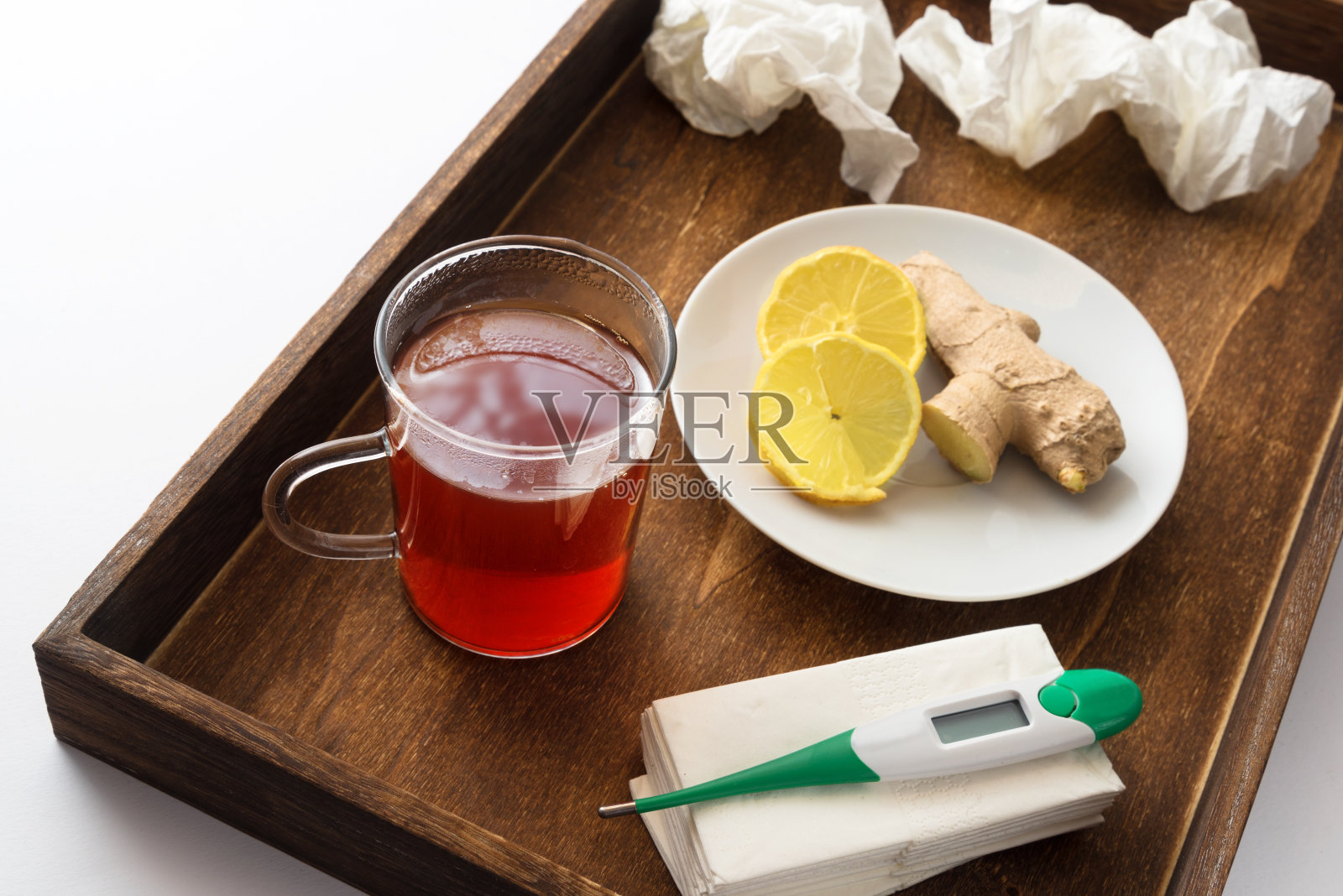 感冒或流感病人用木片，包括热茶、医用体温计、维生素和纸巾，居家治疗的保健理念照片摄影图片