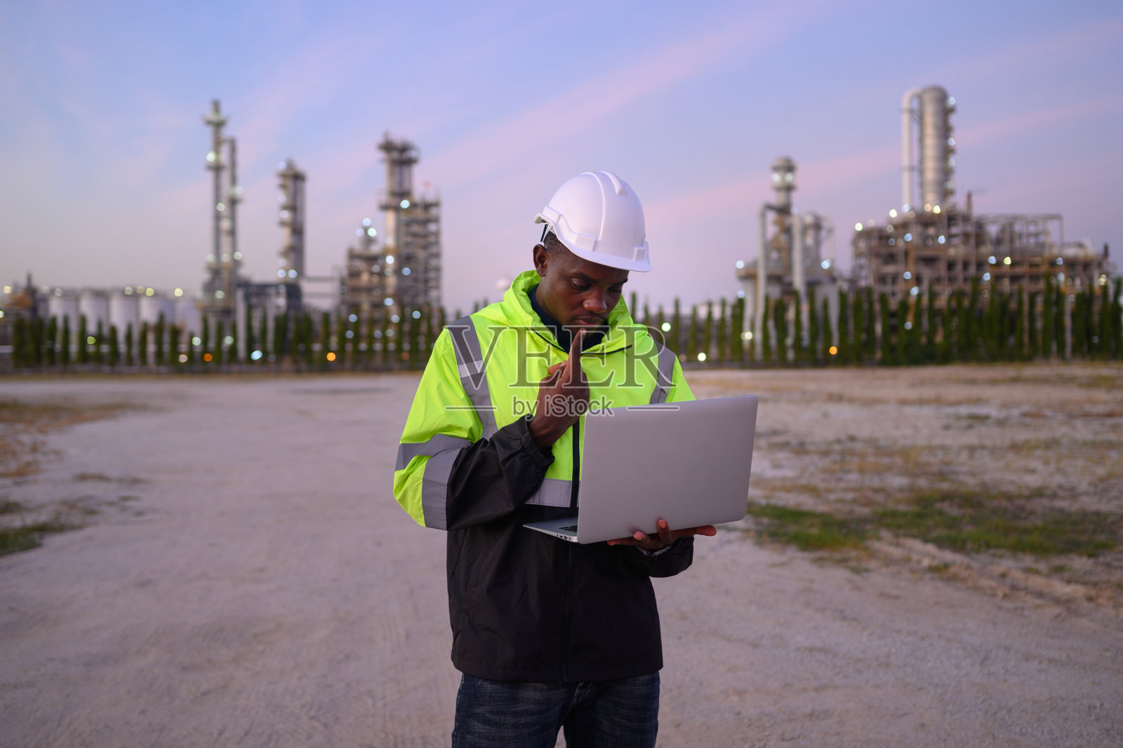男工程师穿着制服，戴着头盔，检查绿色打印项目和无线电和笔记本检查。照片摄影图片