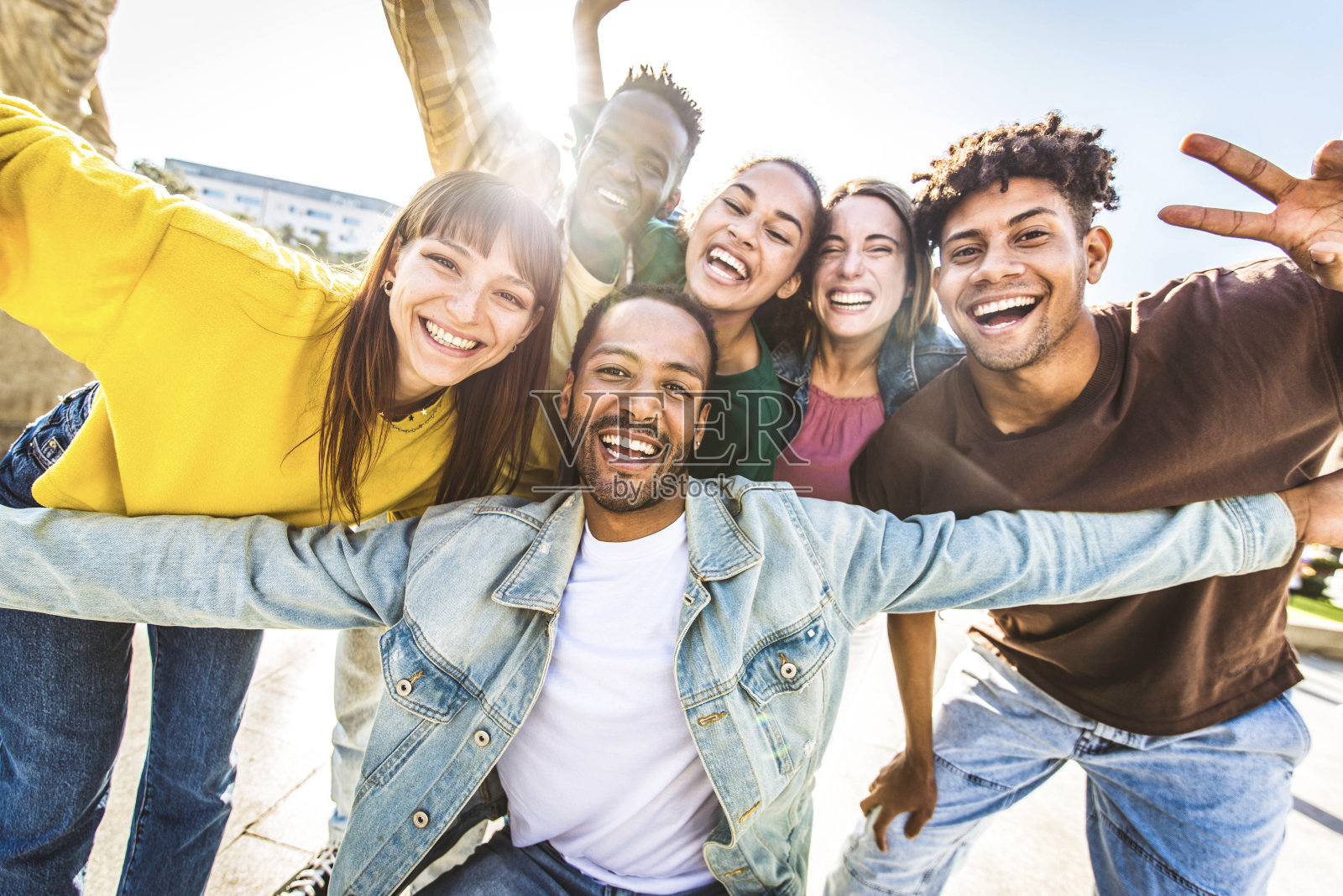 多种族的年轻人在外面对着镜头微笑——快乐的朋友在城市街道上开心地散步——夏日里不同的男孩和女孩在一起的青年社区概念照片摄影图片