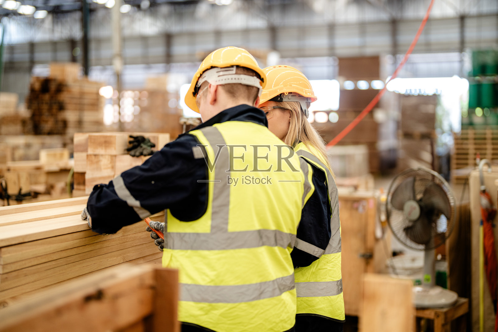 工人们在仓库里行走和检查木材。智能产业工人运营理念。木材厂生产木颚。照片摄影图片