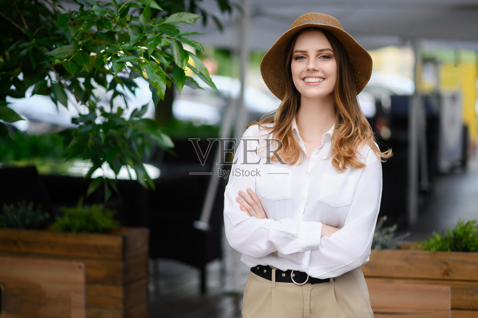 一个戴着帽子双臂交叉的快乐女人的画像，是一个企业主。美的概念，时尚，格调，自信。照片摄影图片