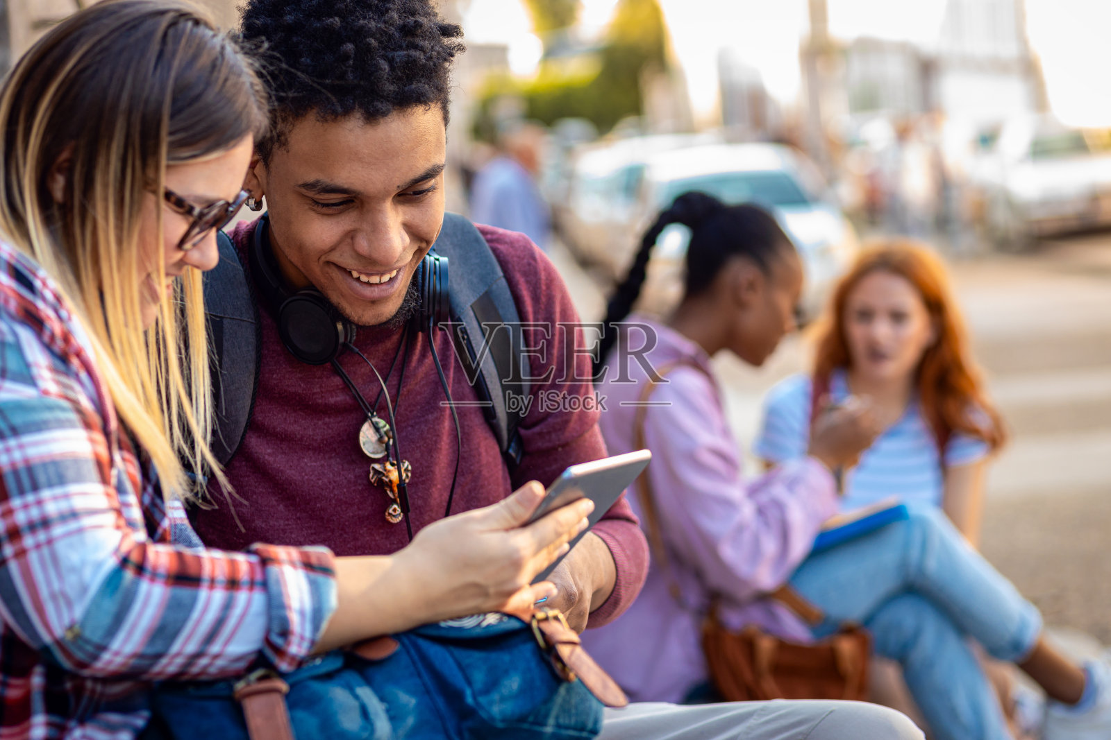 不同群体的学生坐在楼梯上一起聊天和学习。照片摄影图片