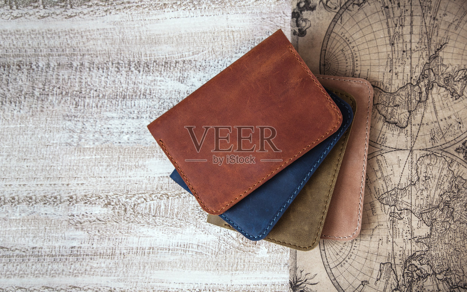 护照封面由不同色调的皮革制成，木质背景上有一张古代地图的图像。现代旅行者必备配件照片摄影图片