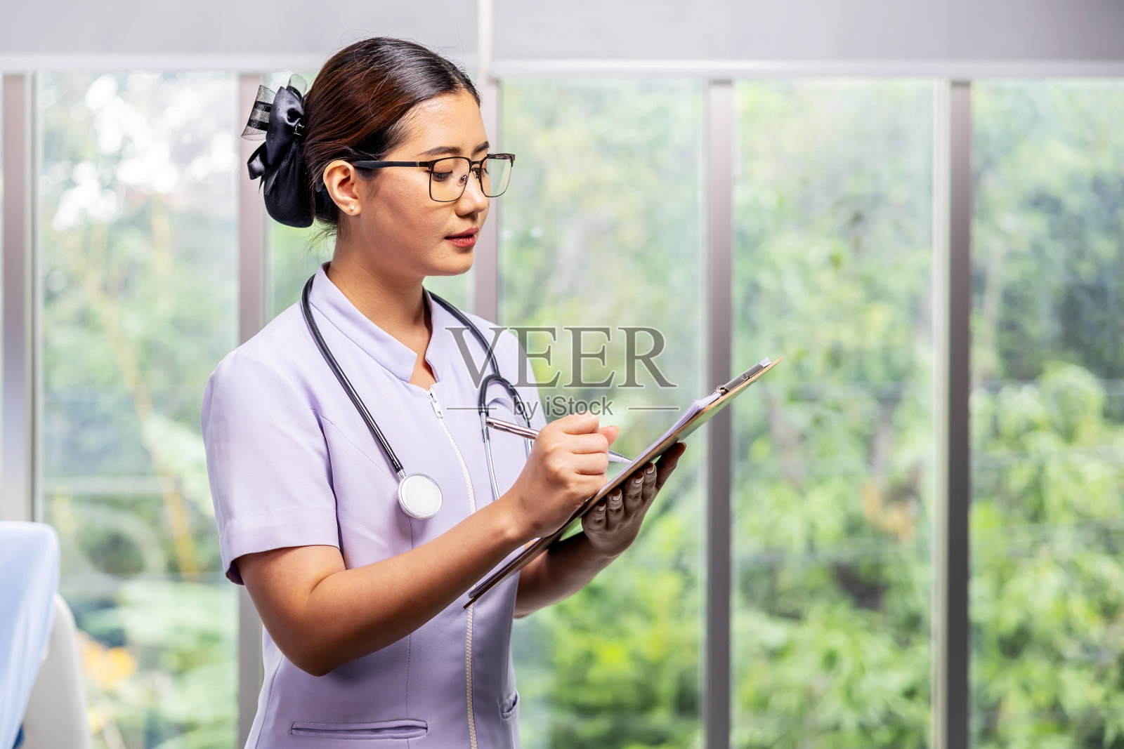 医院里，一名身穿白大褂的亚洲女护士拿着写字板照片摄影图片