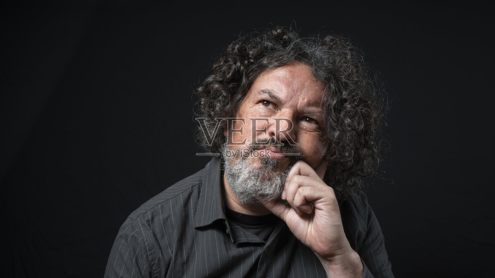 一个留着长长的卷发，穿着黑色衬衫的男人，下巴托在他的照片摄影图片