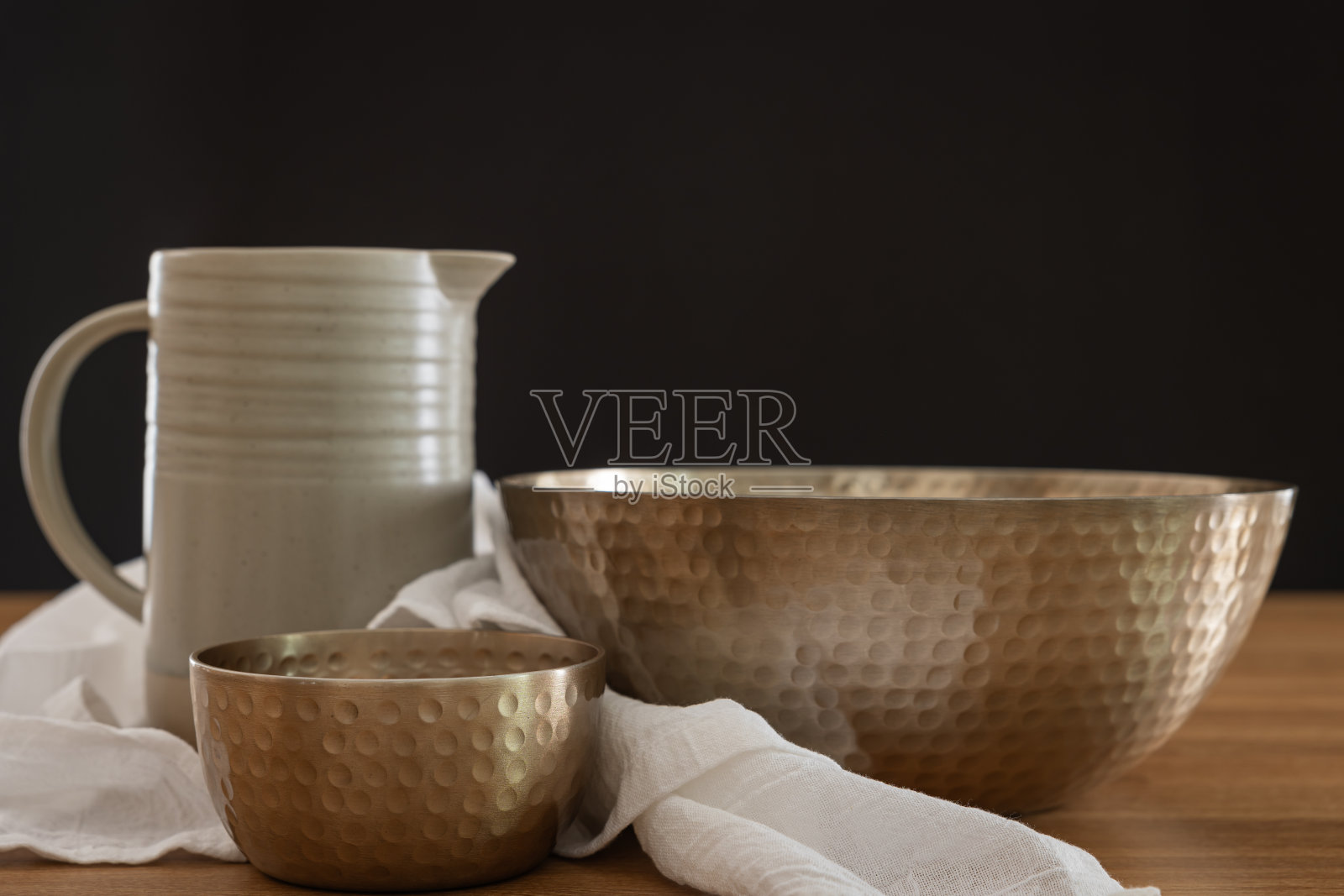 两个铜碗，一个水罐和一块黑底的白色亚麻布照片摄影图片