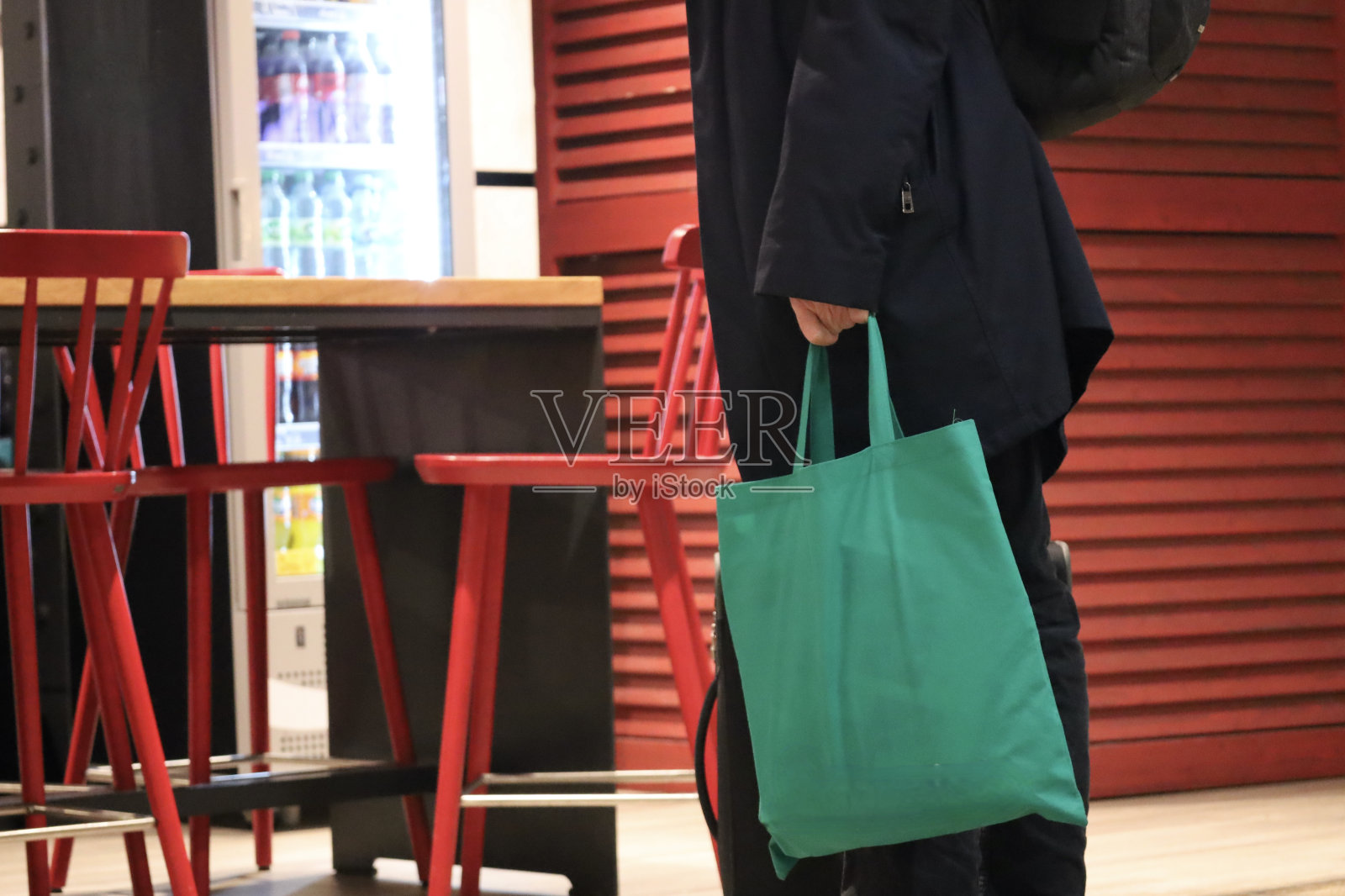 一个拿着绿色袋子的男人站在红椅子前照片摄影图片