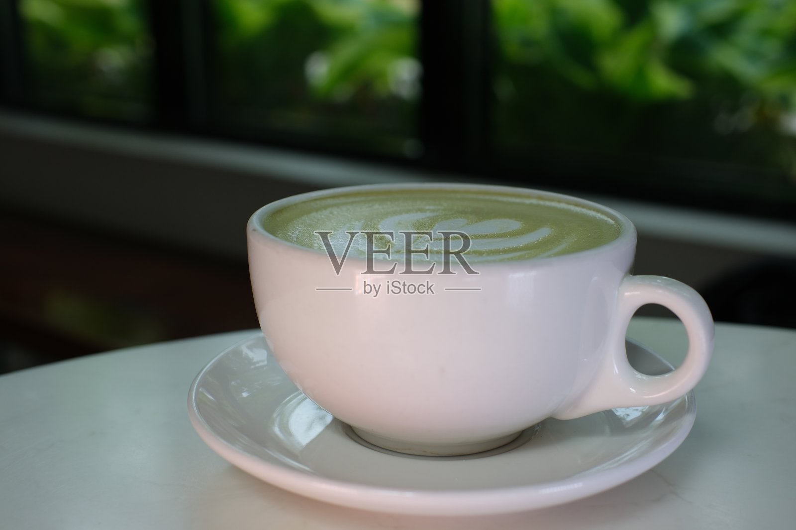 抹茶饮料装在一个白色的杯子里，特写画上绿茶加牛奶，美丽的餐厅，明天的晚餐。饮食照片摄影图片