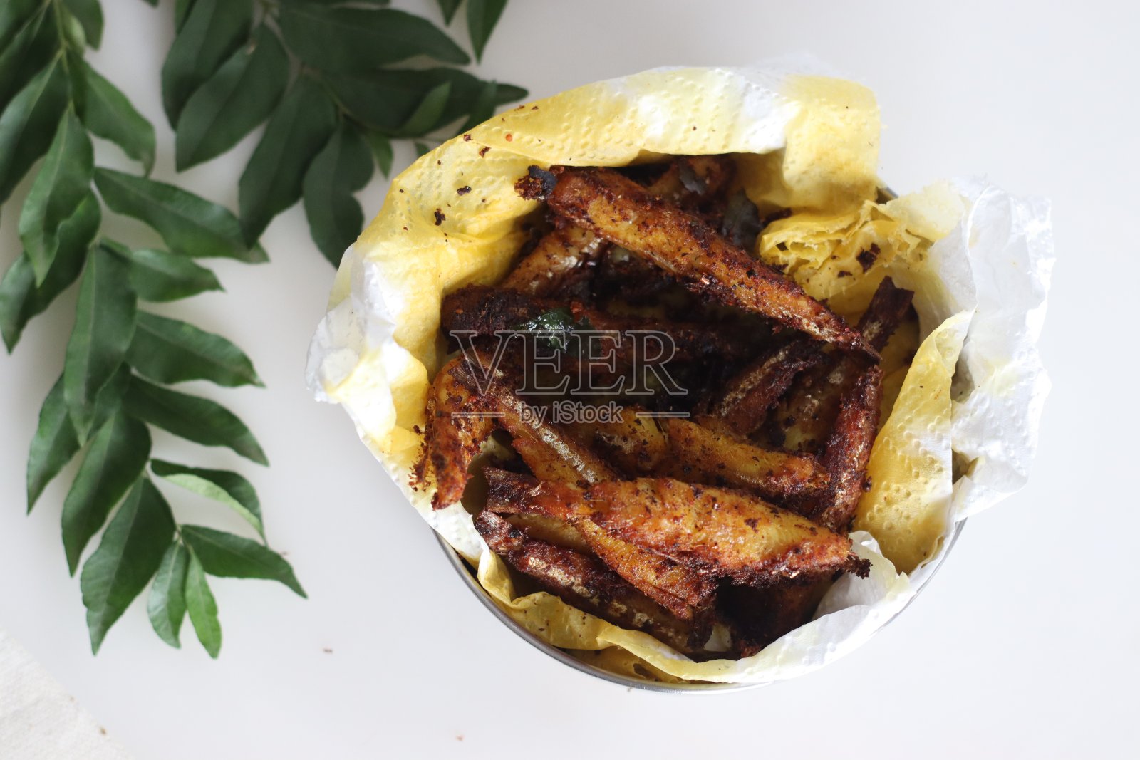 美味的凤尾鱼煎炸，酥脆金黄，配上配菜上桌照片摄影图片