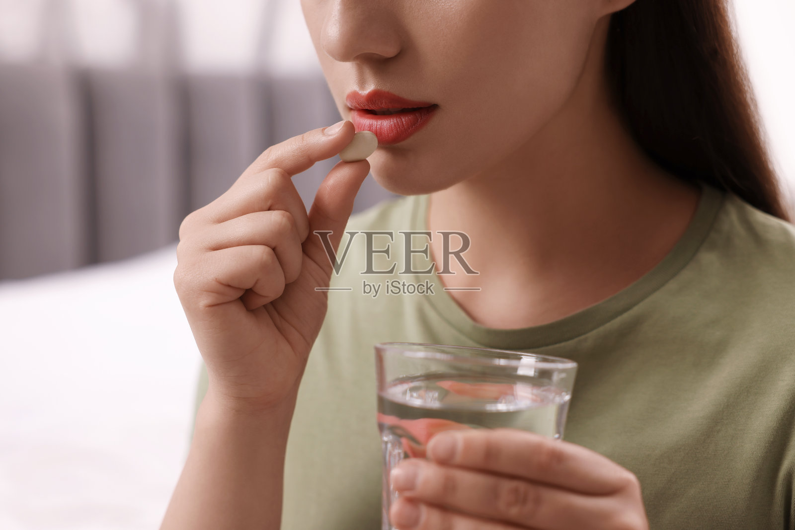 一个女人拿着一杯水在室内服用抗抑郁药，特写照片摄影图片