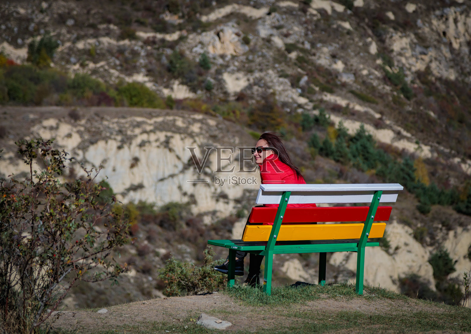 以山为背景的女孩坐在长凳上照片摄影图片