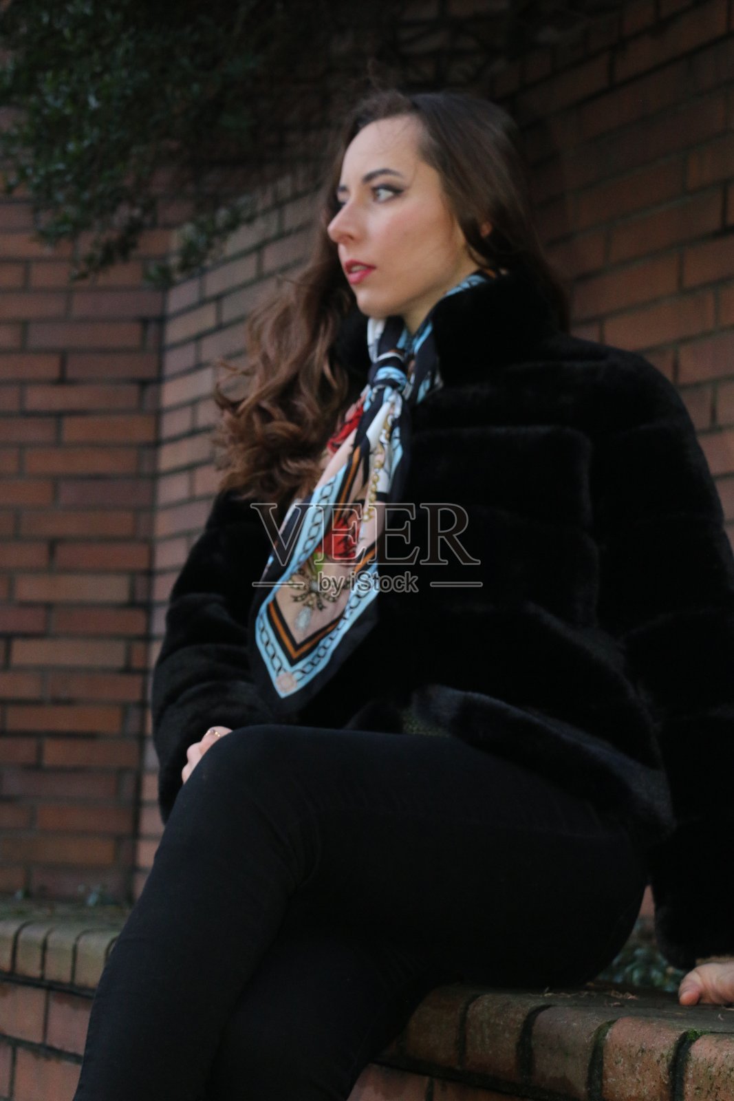 坐在砖墙上照片摄影图片