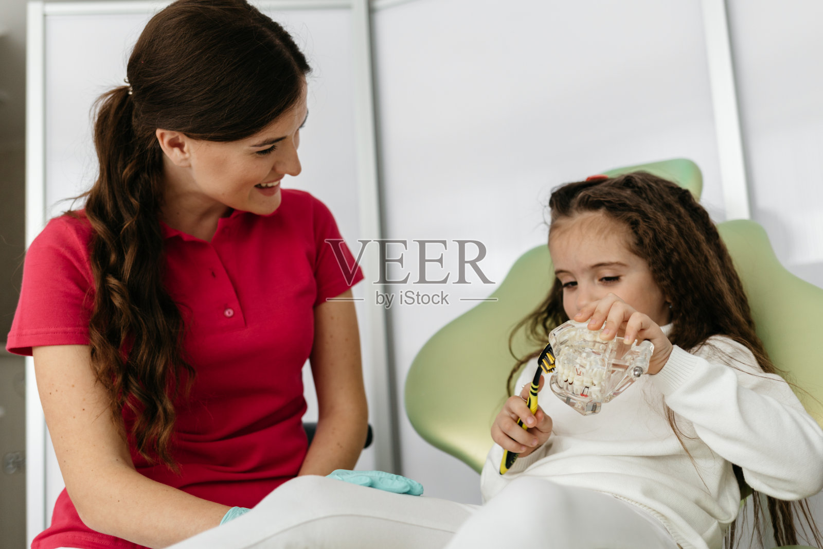 一个女孩在牙医的办公室里示范如何刷牙照片摄影图片