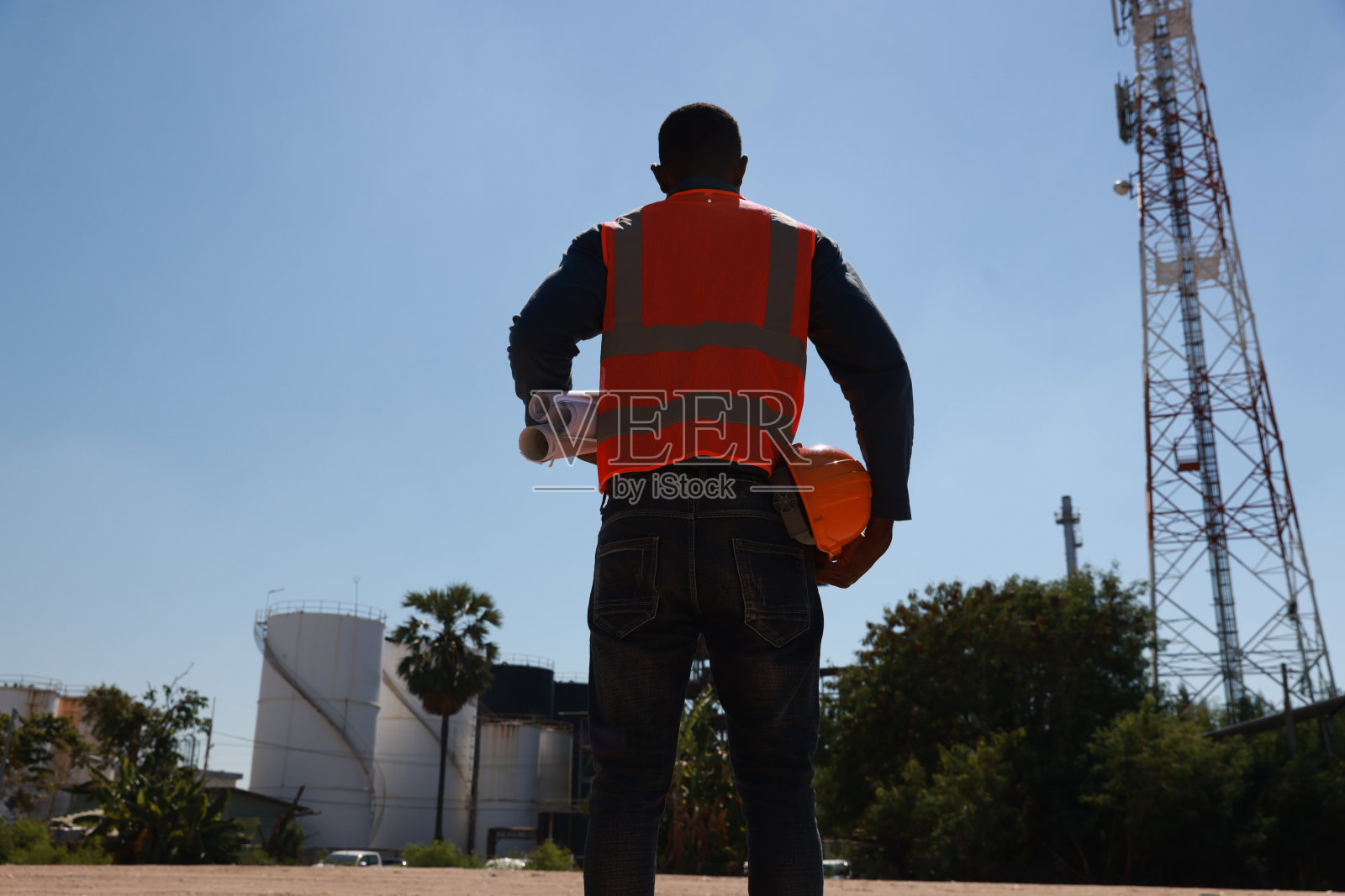 土木工程师手持图纸和安全帽在施工现场前的特写肖像照片摄影图片