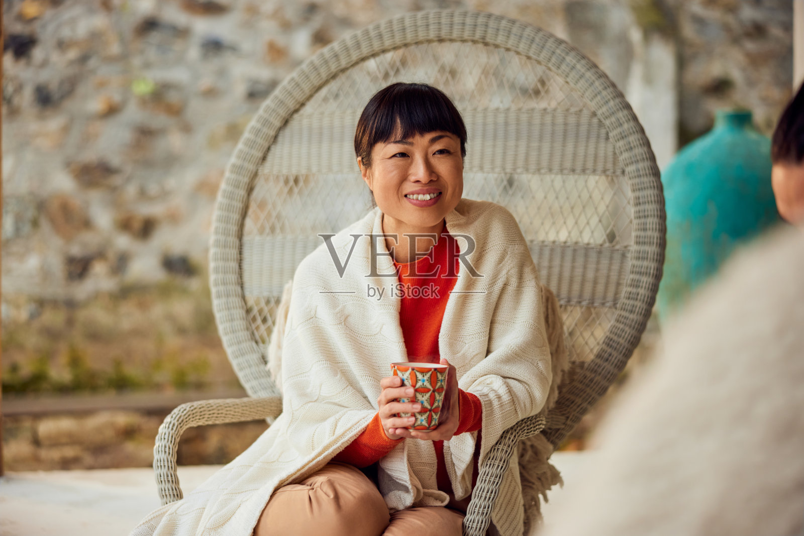 一个微笑的亚洲女人和她的朋友聊天，坐在户外的露台上。照片摄影图片